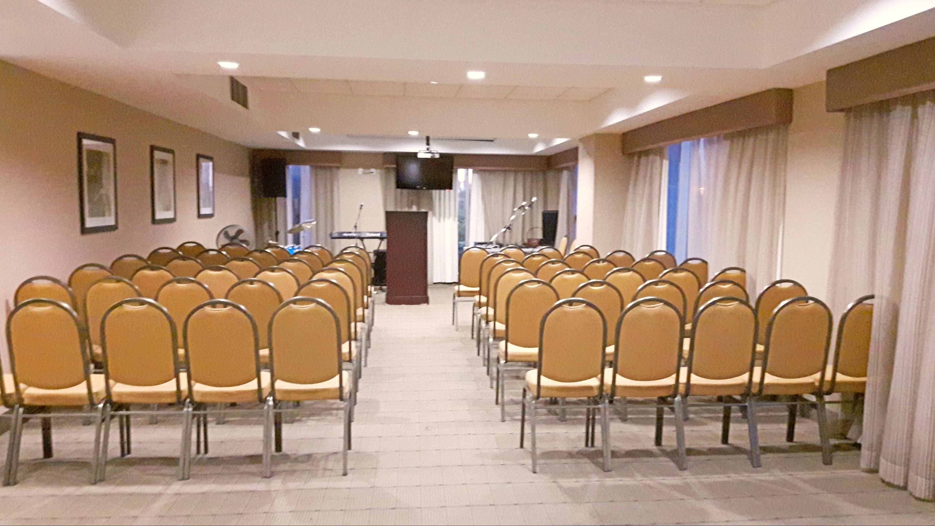 A conference room with rows of chairs facing a podium.