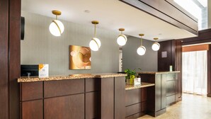 A reception desk with a dark wood finish, a granite countertop, and a modern light fixture. - Comfort Inn & Conference Centre Toronto Airport (Toronto)