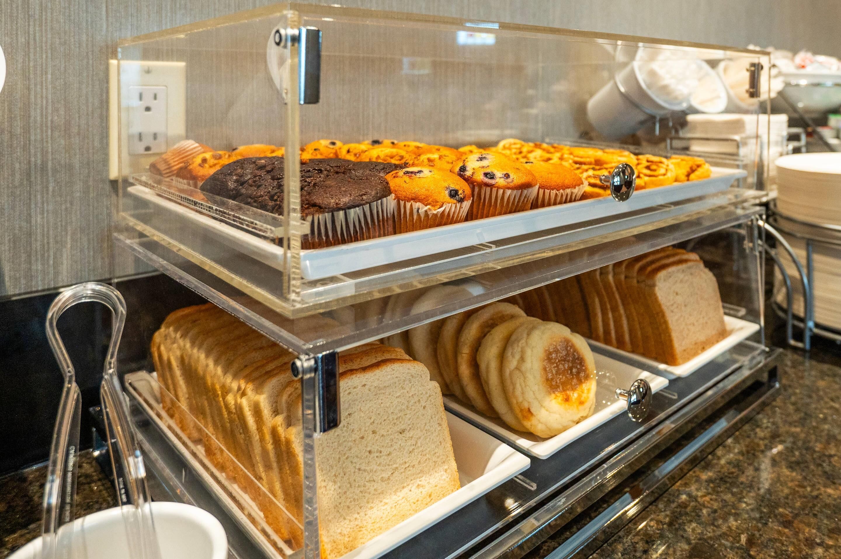 A buffet counter with various baked goods including muffins, cookies, and bread.