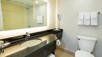 Un baño con lavamanos, espejo, inodoro y perchero para toallas.