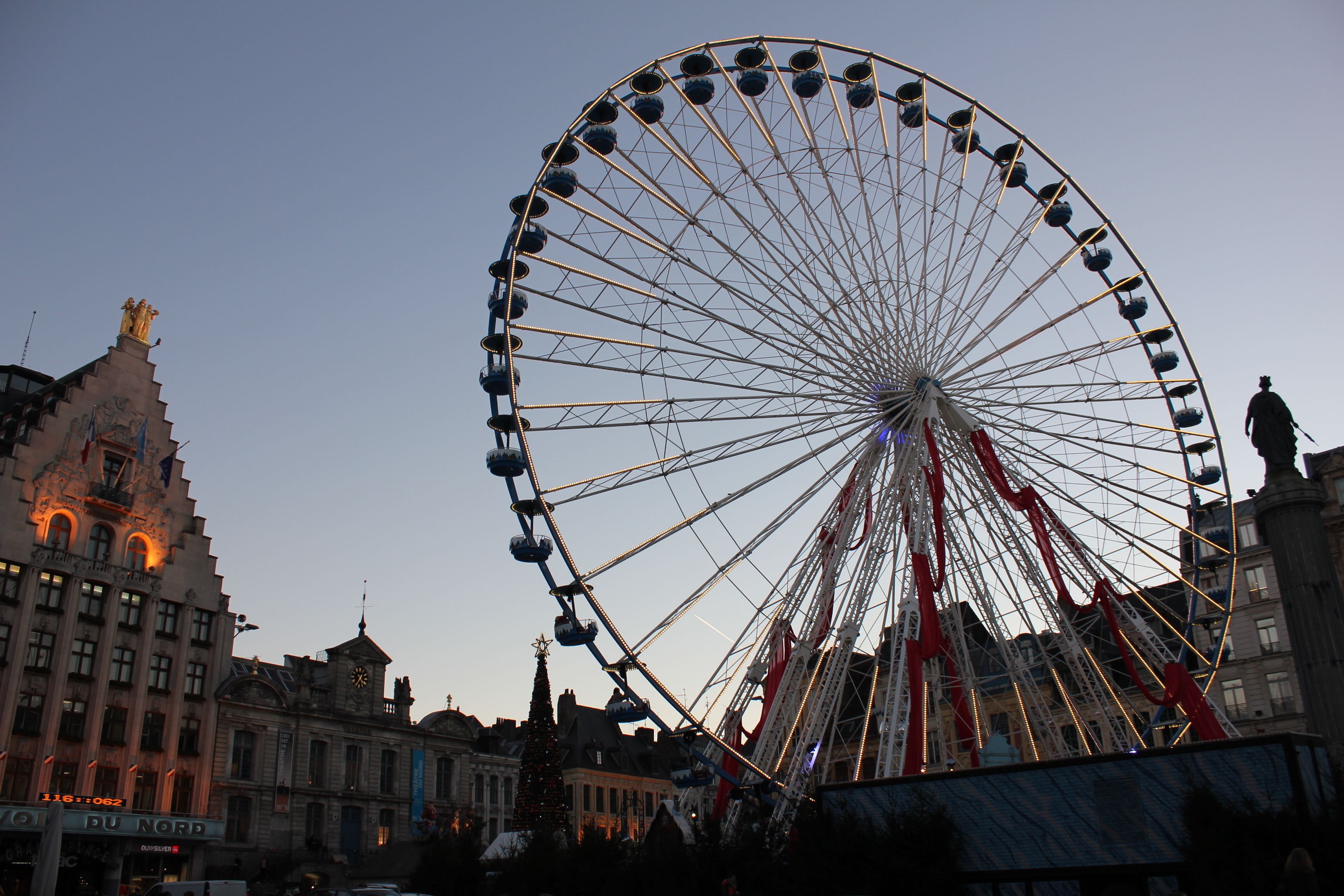 Ein großes Riesenrad in einer Stadtlandschaft mit historischen Gebäuden im Hintergrund.