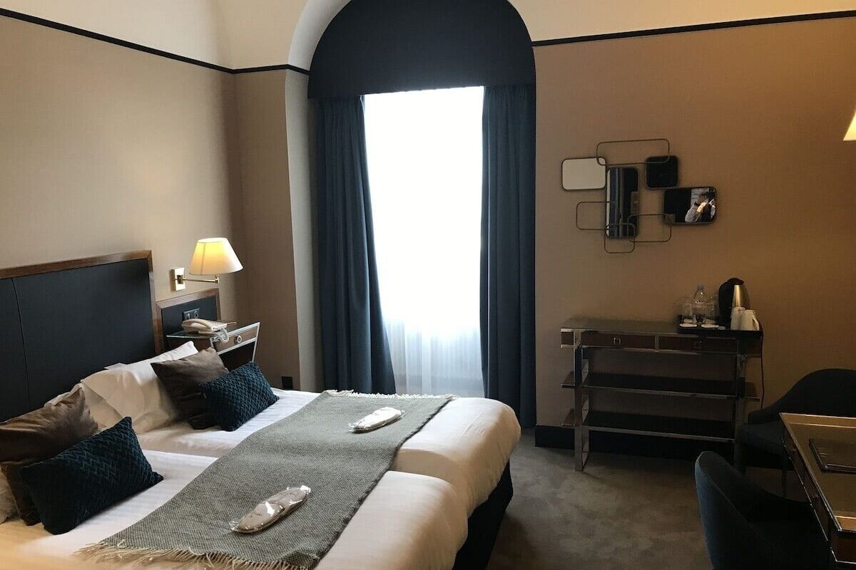 Una habitación de hotel con cama, mesitas de noche, escritorio y silla.