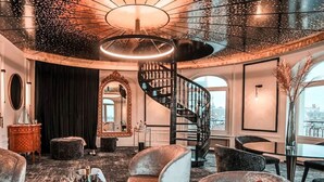 Een weelderig interieur met een statige trap, elegant meubilair en grote ramen met uitzicht over de stad.
