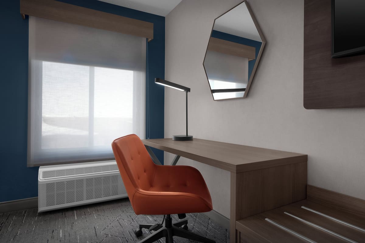 A modern office space with a desk, chair, and a large window with blinds.