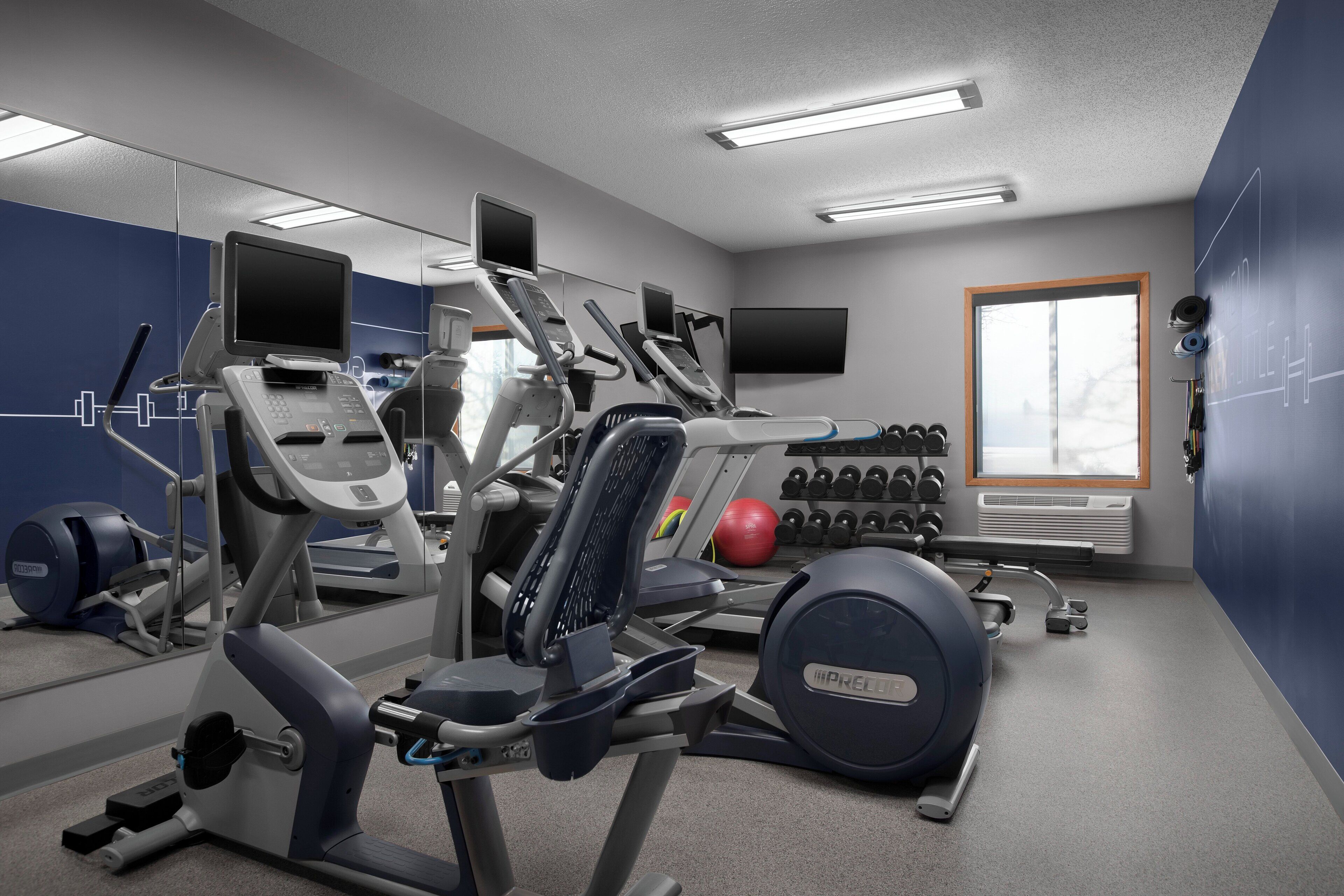 Une salle de sport équipée de machines de cardio, de matériel de musculation et dotée d’un mur recouvert de miroirs.