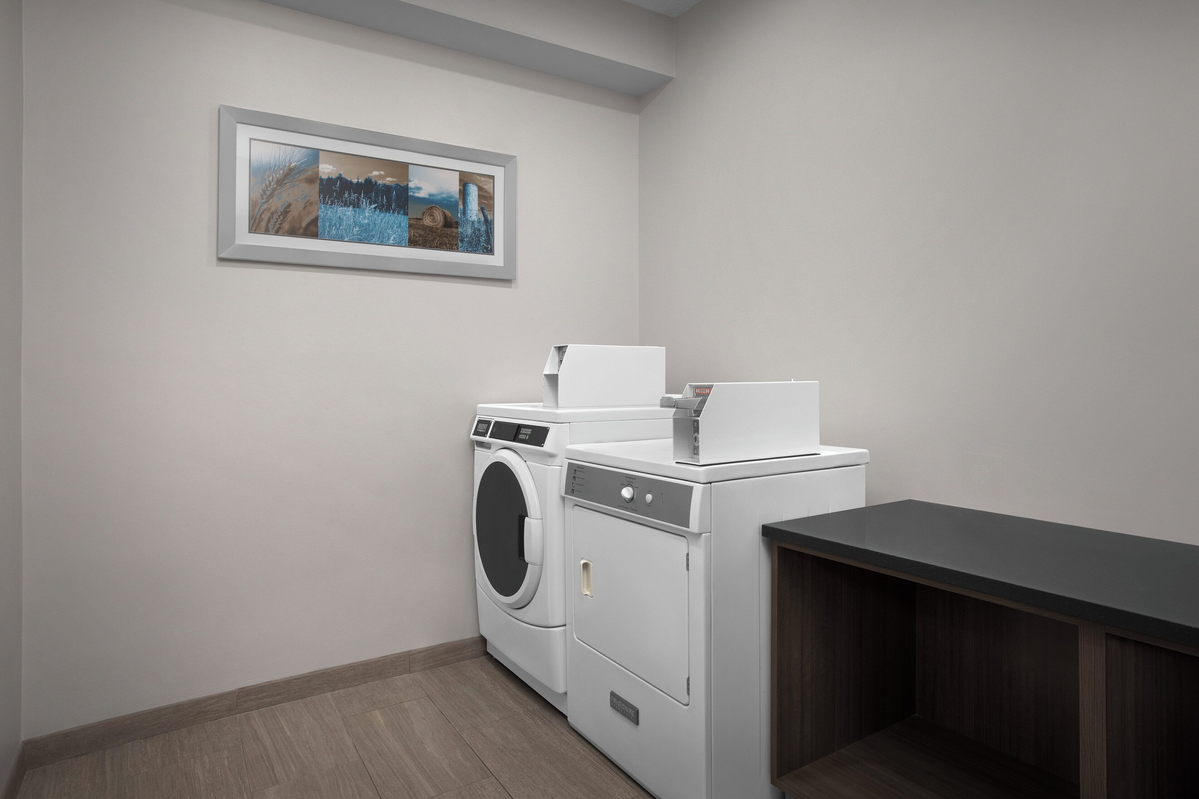 A laundry room with a washing machine, dryer, and a small table with a basket.