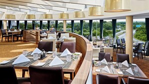 Un restaurante moderno con techos altos, ventanas amplias y vistas a la ciudad.