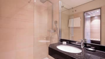 Une salle de bain moderne avec une douche à parois de verre, un lavabo blanc et un grand miroir.