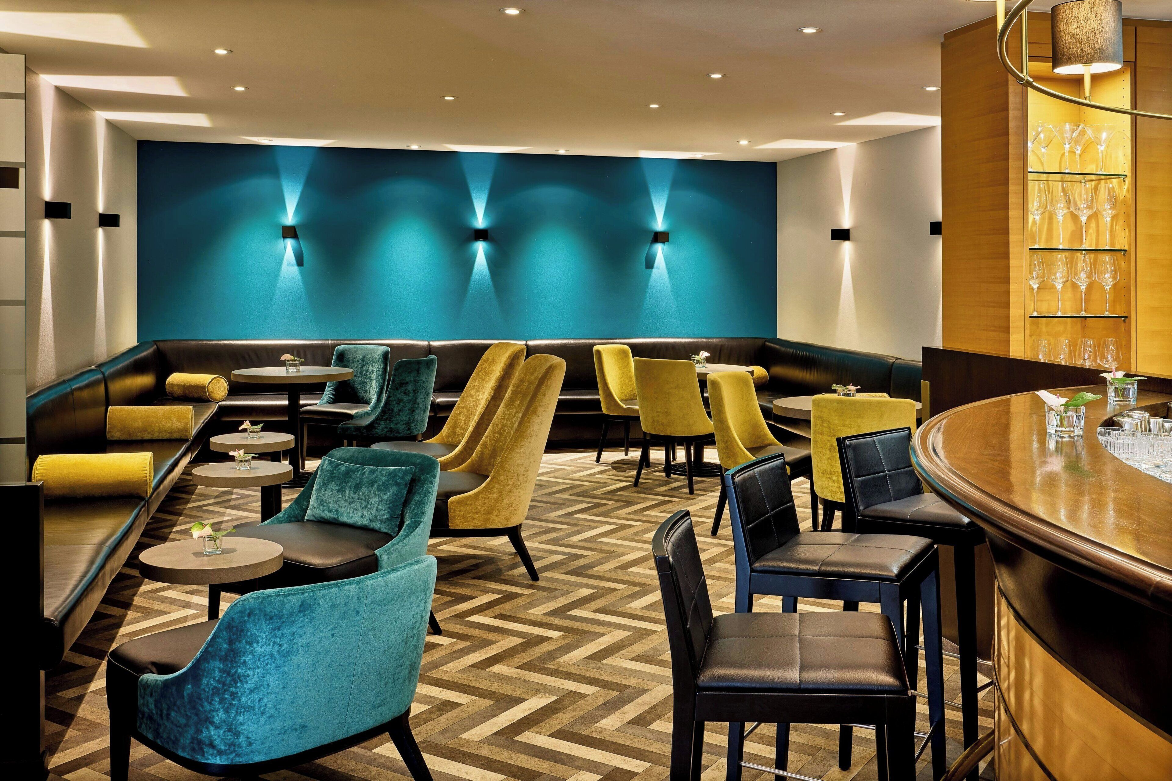 Un espace de détente moderne avec un parquet en chevrons, un bar et différents types de sièges, notamment des canapés et des fauteuils.