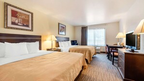 A hotel room with two beds, a desk, a television, and a window with curtains. - Quality Inn & Suites Limon (Limon)