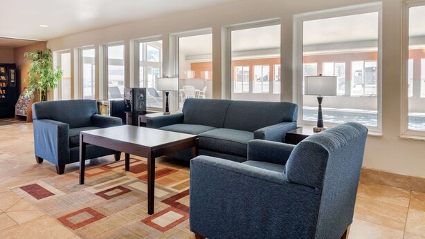 A modern living room with a sectional sofa, a coffee table, and a TV. Large windows provide a view of the outside. - Quality Inn & Suites Limon (Limon)