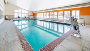 An indoor swimming pool with clear blue water, surrounded by white lounge chairs and a lifeguard stand. - Quality Inn & Suites Limon (Limon)