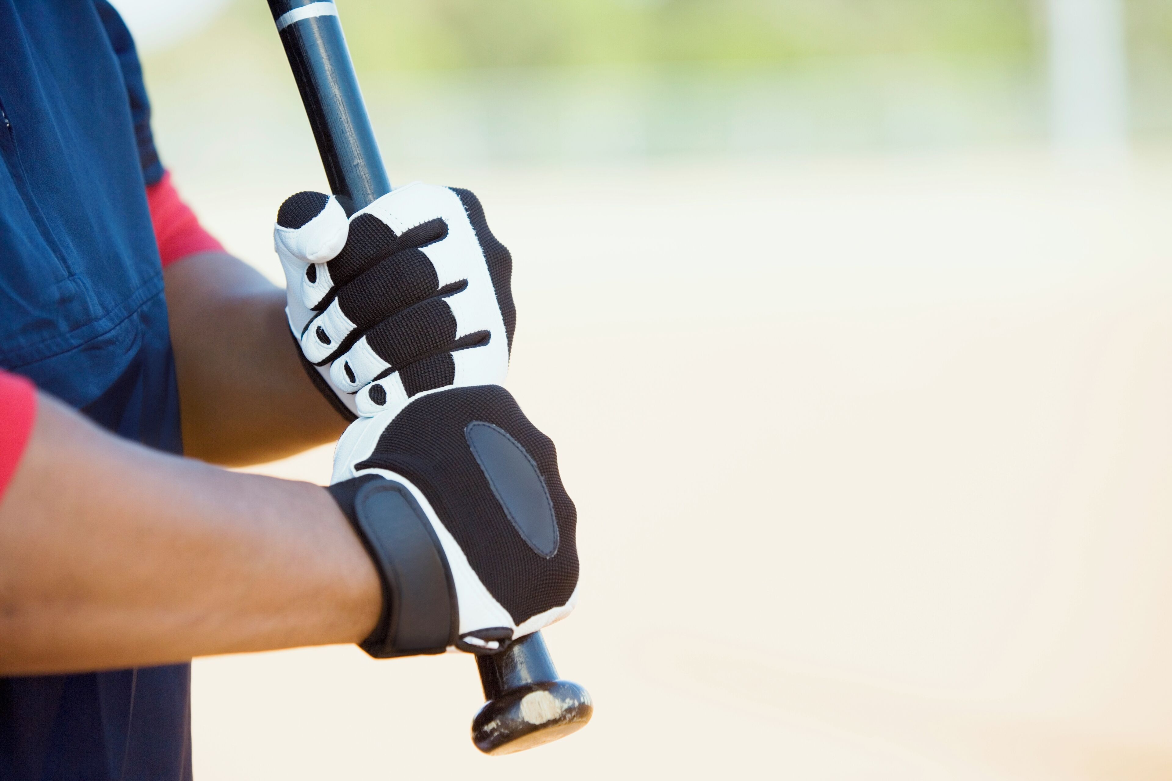 A close-up of a baseball glove with a black and white design, held by a person wearing a blue shirt.