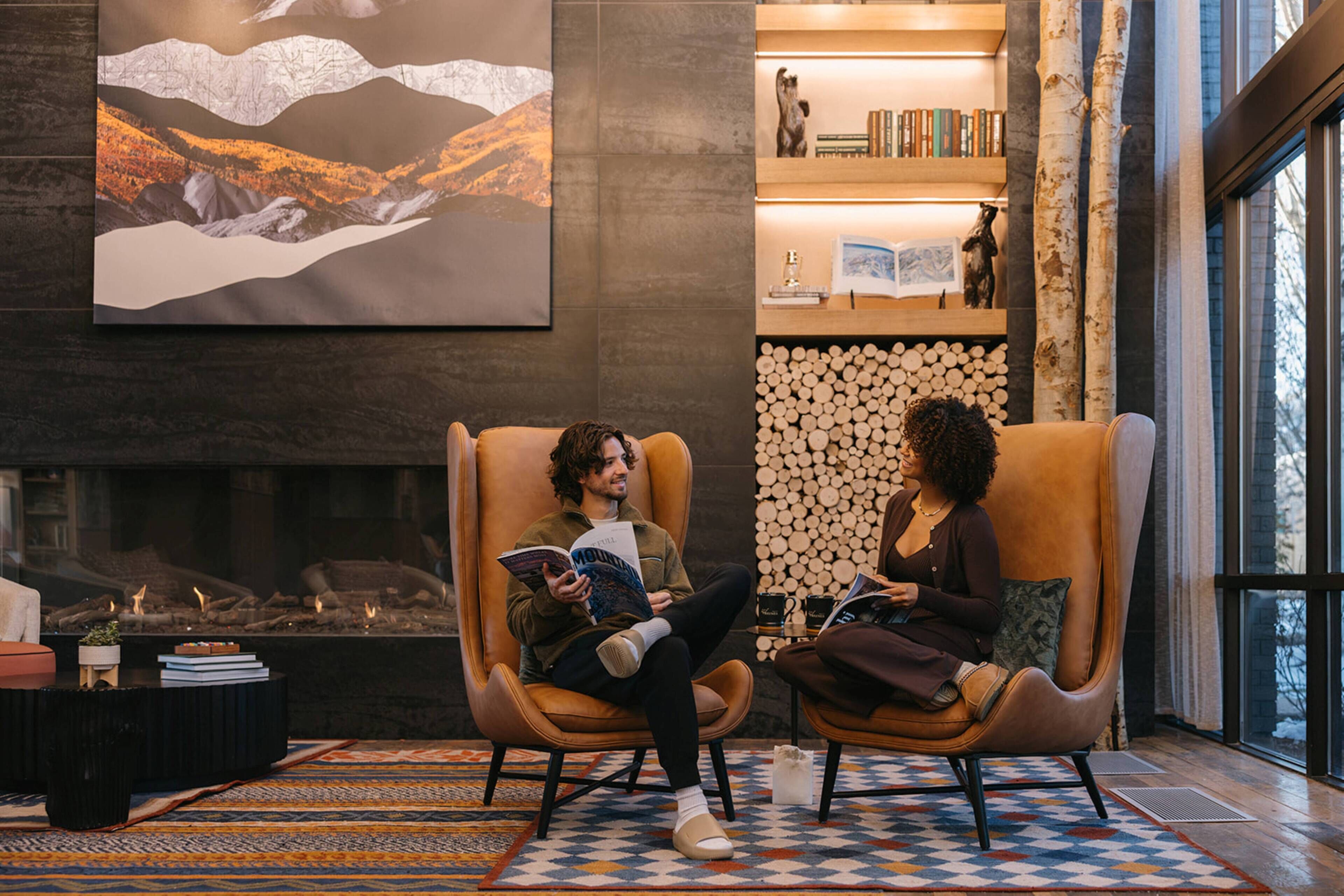 Two armchairs in a cozy room with a fireplace, a bookshelf, and a large painting on the wall.