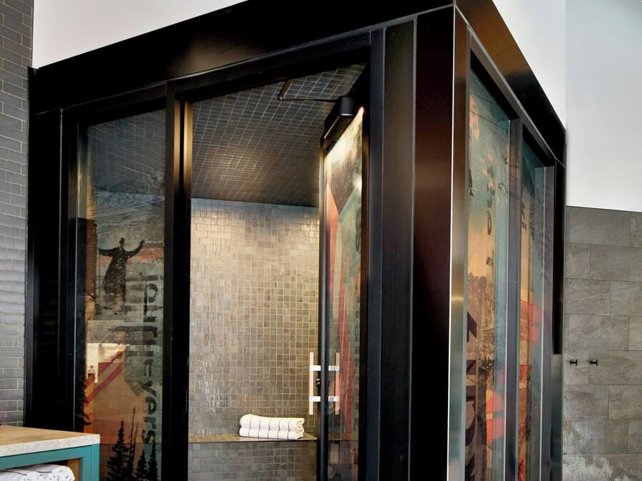 Ein modernes Badezimmer mit Glasabtrennung, Holzboden und Fliesenwand.
