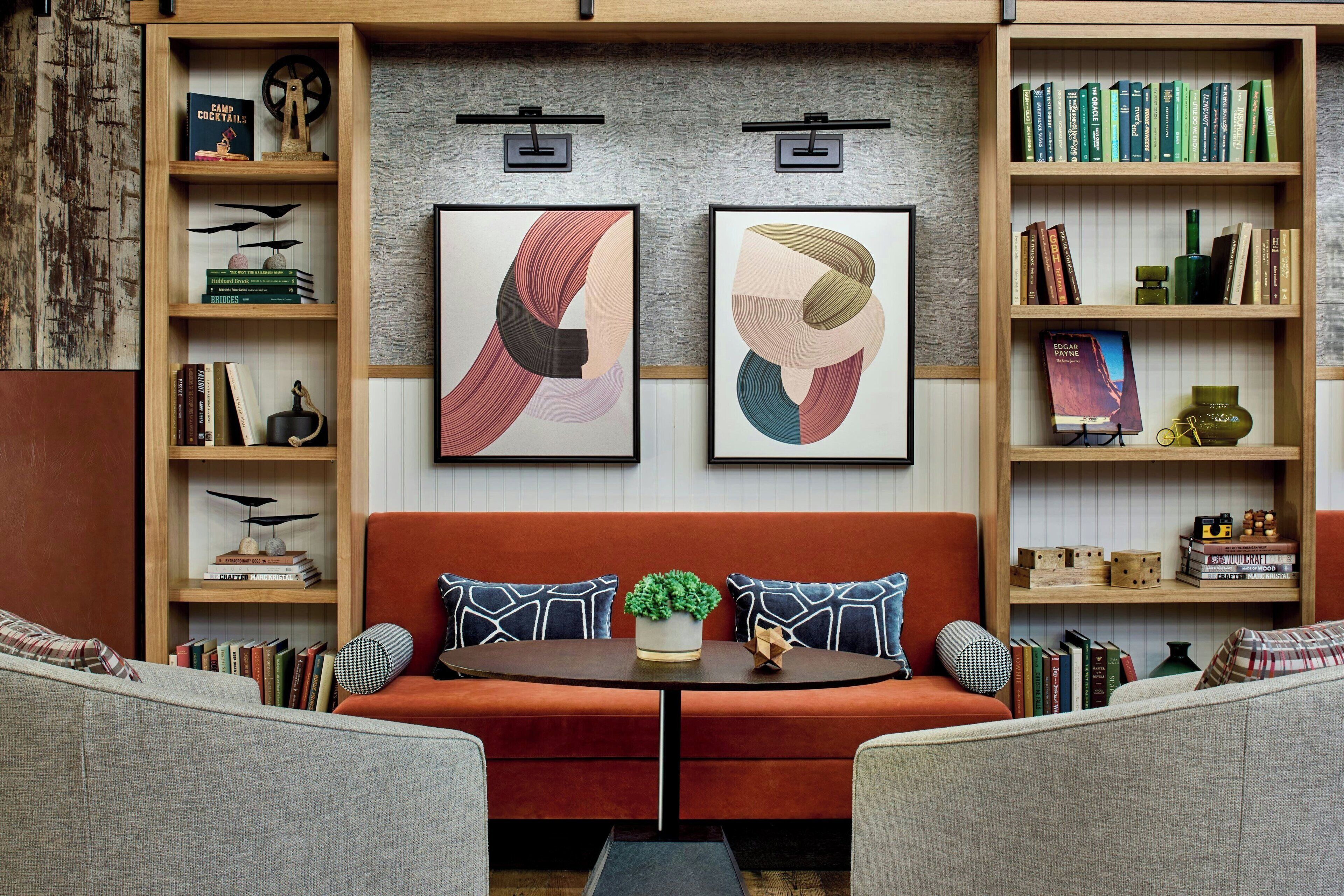 A cozy living room with a red sofa, a coffee table with a plant, and bookshelves filled with books and decorative items.