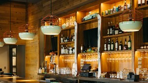 A bar with wooden paneling, metal bar stools, and a variety of bottles and glasses on shelves. - Hotel Thaynes, Park City, a Tribute Portfolio Hotel (Park City)