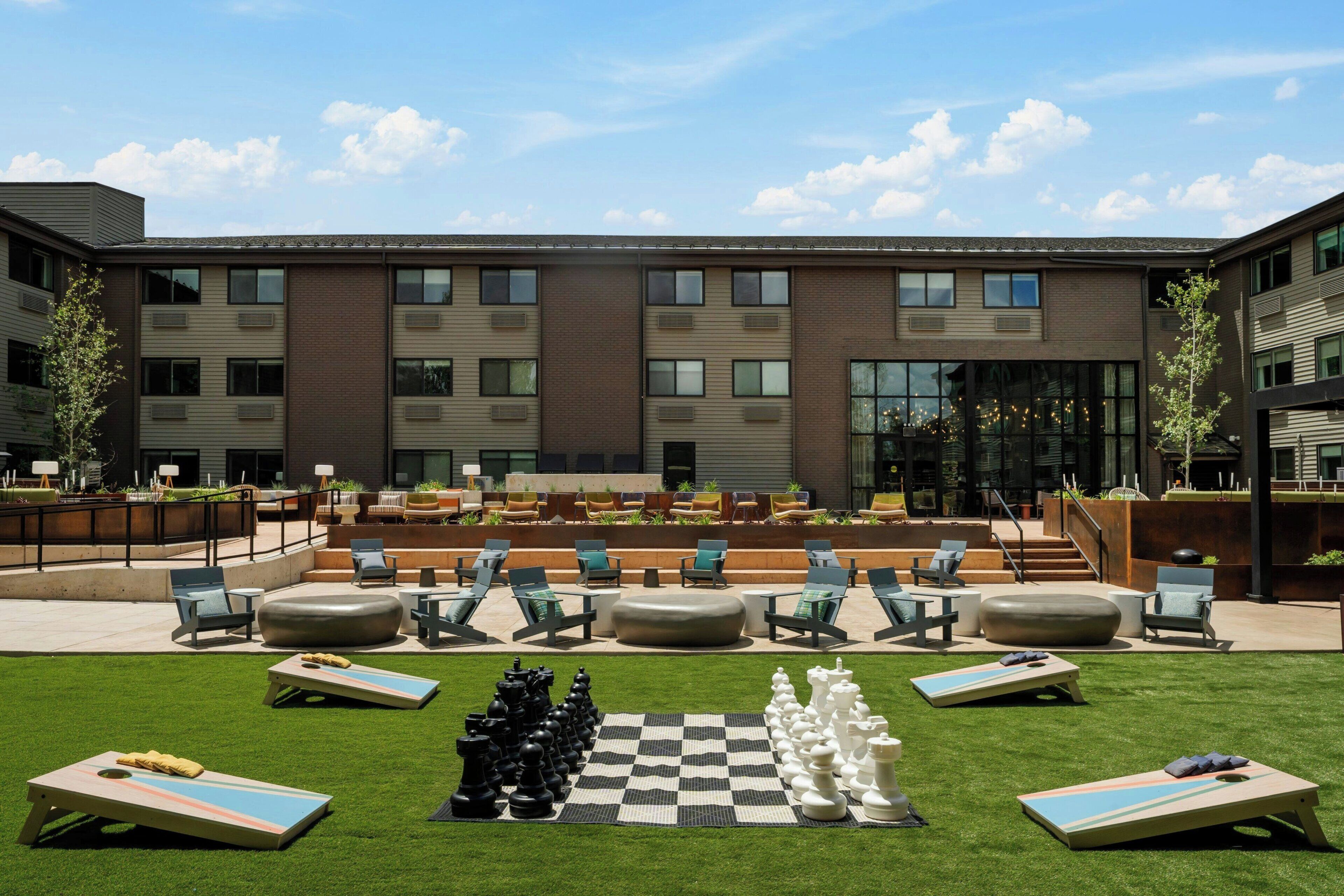 Un patio con mobiliario exterior, un tablero de ajedrez y un edificio con varias ventanas.