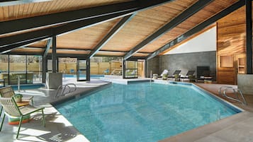 Una piscina techada, una piscina al aire libre, sombrillas