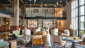 A spacious lobby with high ceilings, exposed wooden beams, and hanging light fixtures. There are multiple seating areas with modern furniture and a large, colorful patterned carpet. - Hotel Thaynes, Park City, a Tribute Portfolio Hotel (Park City)