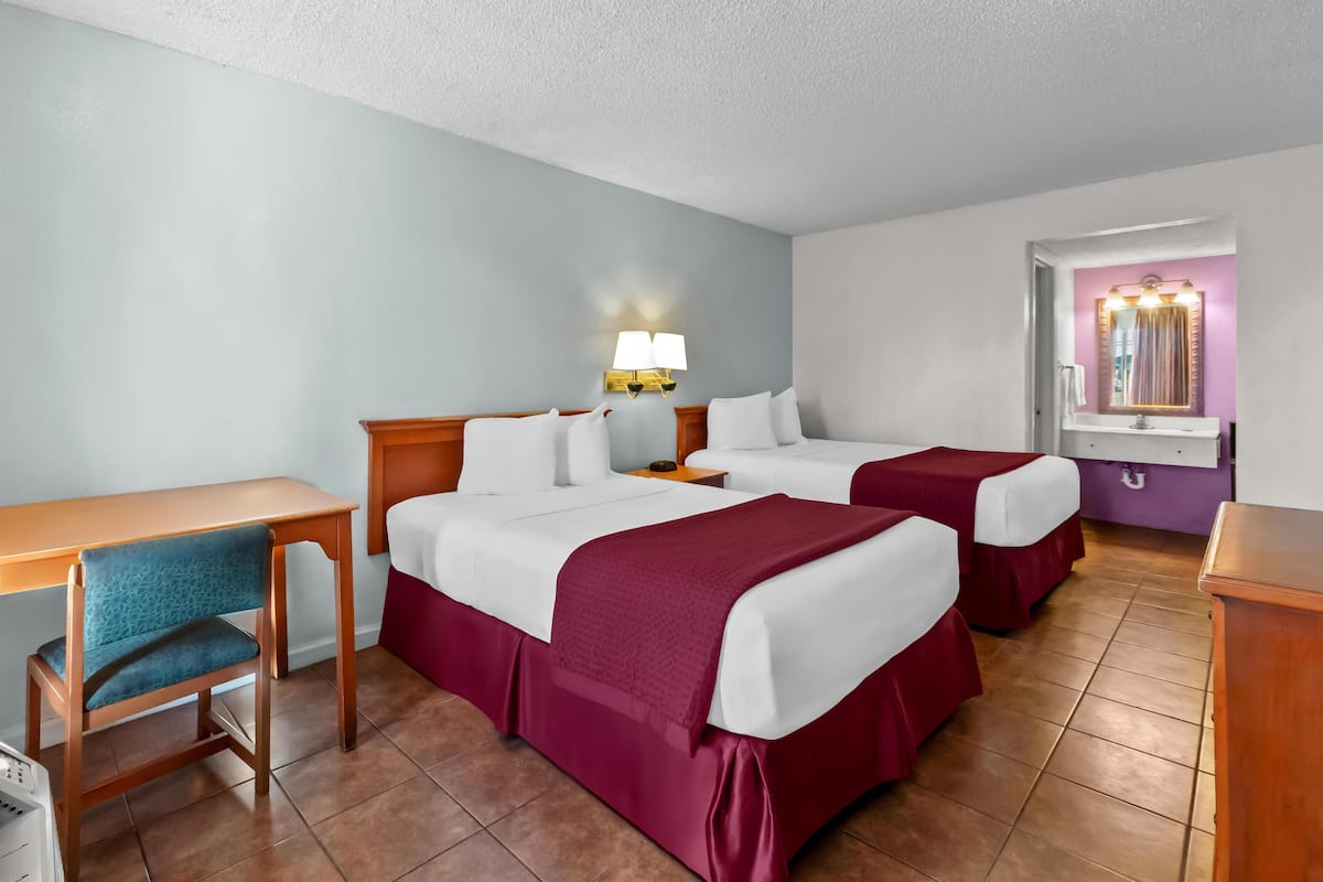 Een hotelkamer met twee bedden, een bureau, een stoel en een kaptafel met spiegel.