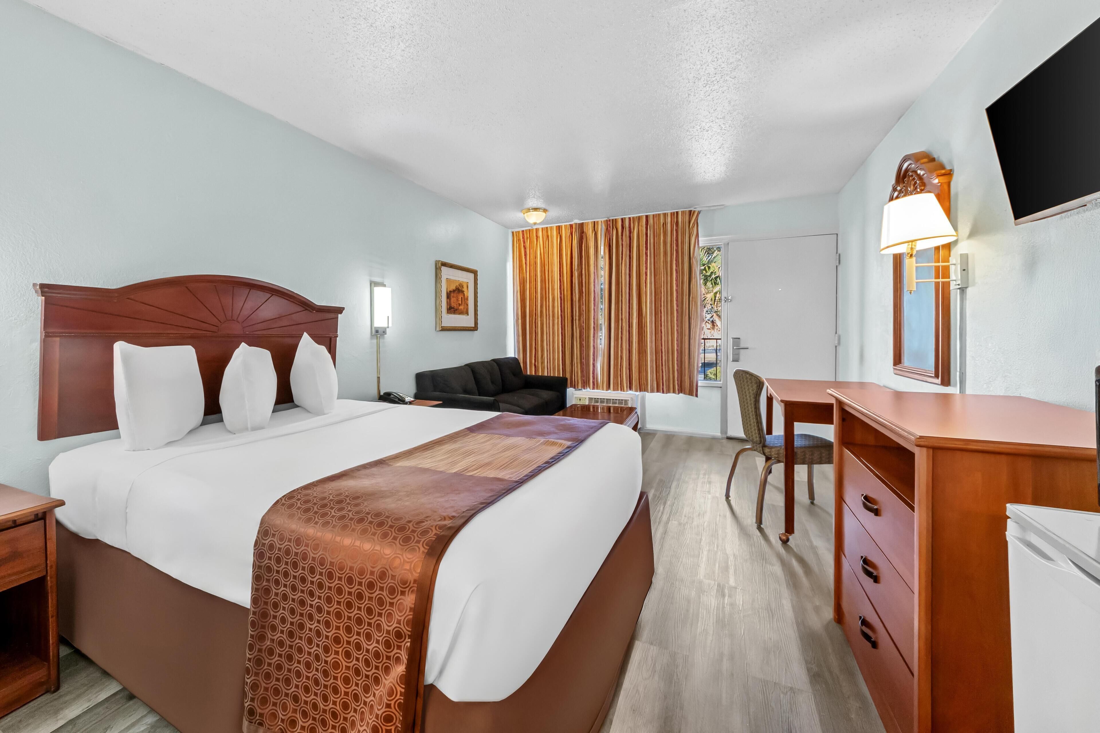Una habitación de hotel con una cama grande, un escritorio, una silla y una televisión.