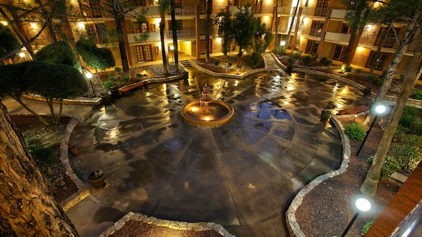 A courtyard with a central fountain, surrounded by trees and illuminated by street lamps. - DoubleTree Suites by Hilton Tucson Airport (Tucson)