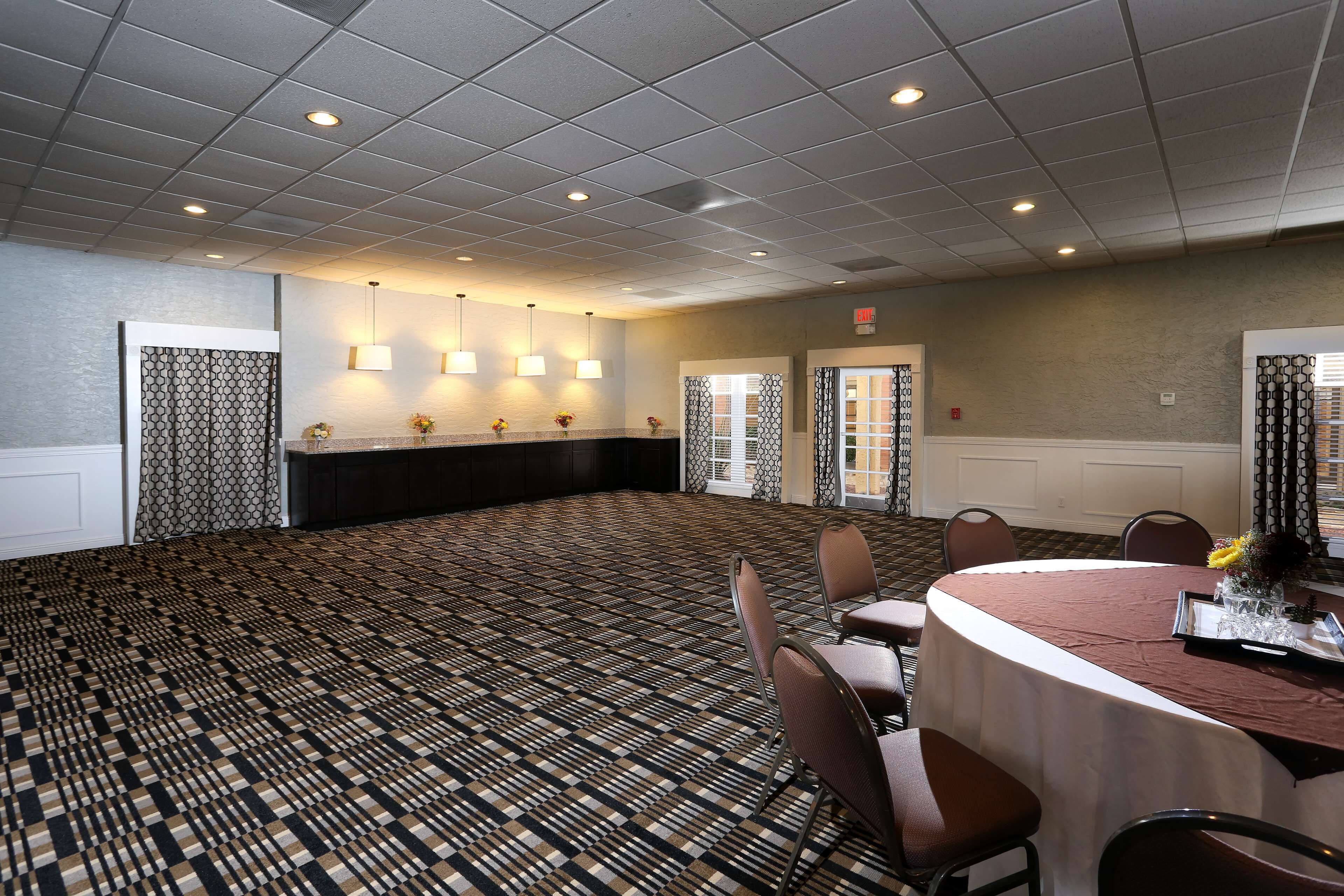 A conference room with a patterned carpet, round table, and chairs.