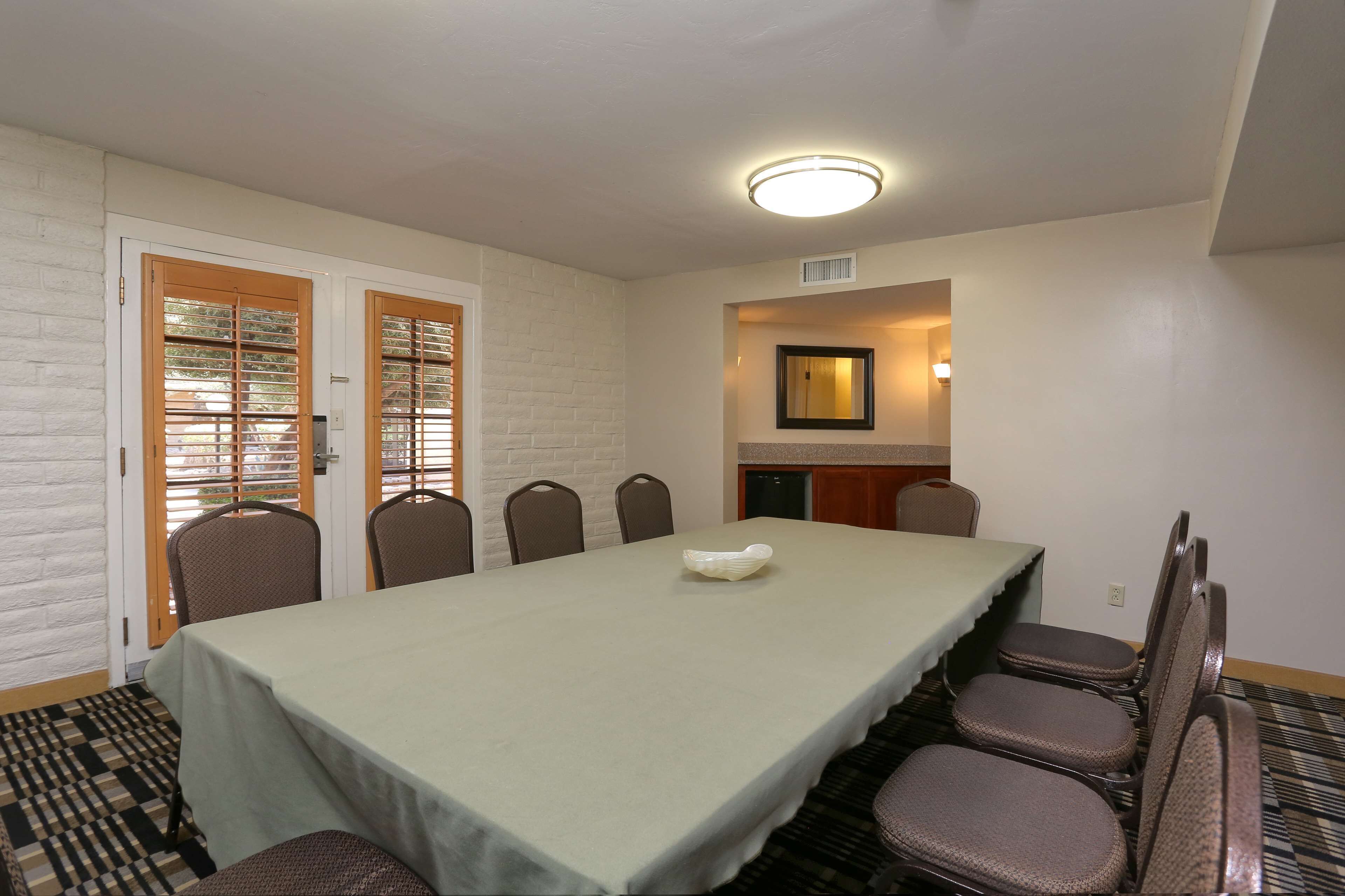 A conference room with a long table, six chairs, and a white tablecloth.