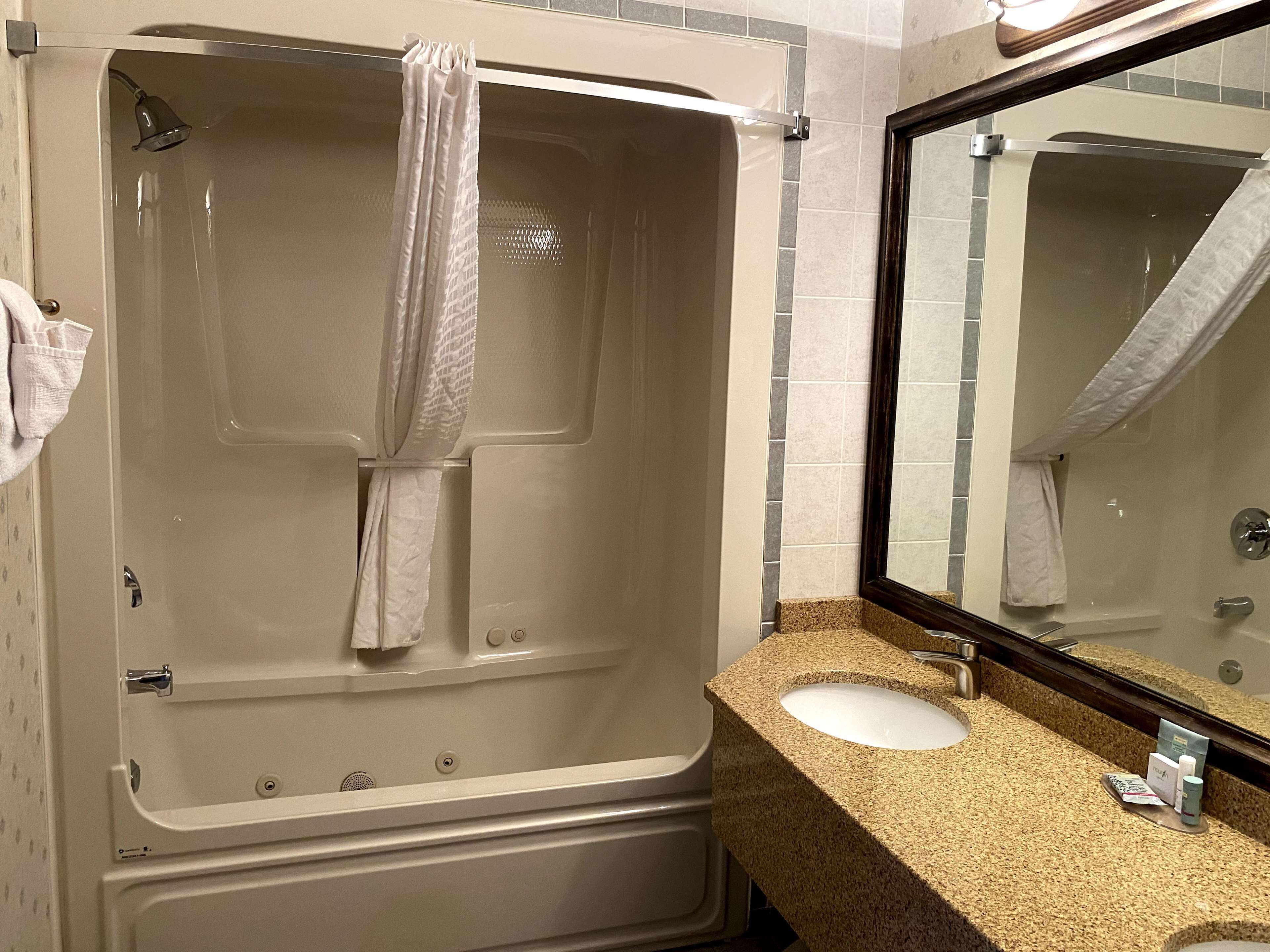 Un baño con bañera, lavamanos y espejo.
