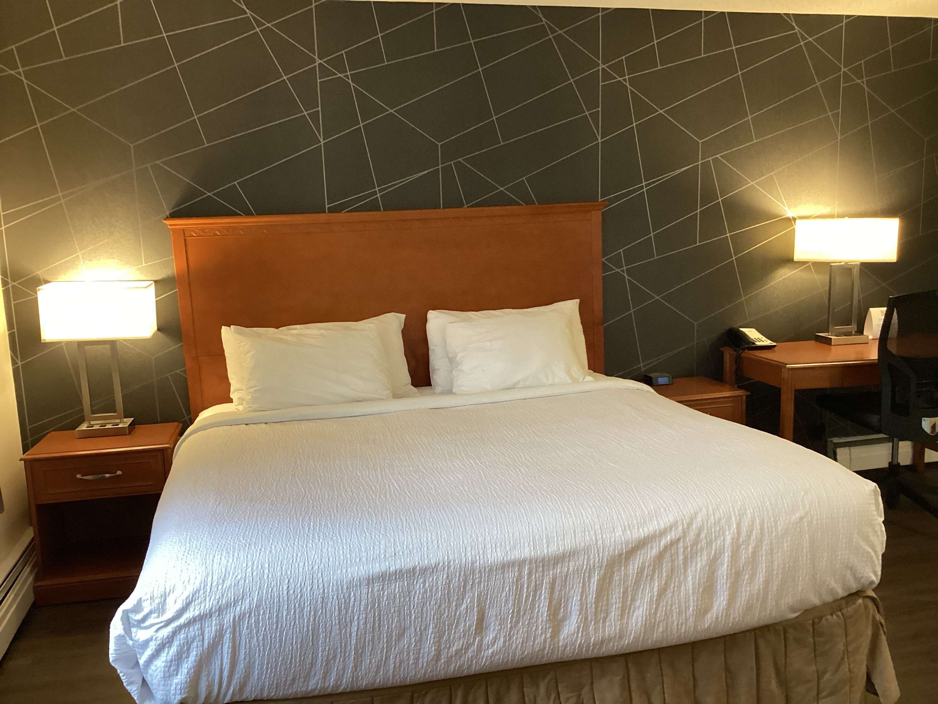 Una habitación de hotel con una cama grande, dos mesitas de noche, un escritorio y una silla.