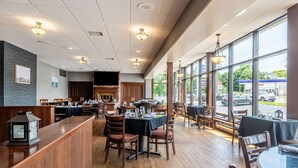 Un restaurant doté d’un plancher en bois, de tables dressées pour le service et de grandes fenêtres donnant sur la rue.