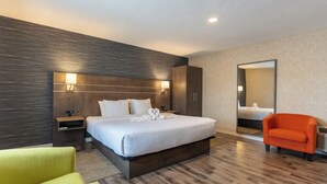 Une chambre d’hôtel moderne avec un grand lit, une table de chevet, un miroir et un fauteuil orange vif.