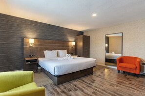 Relax in a stylish space with a large bed, bedside table, and comfortable armchair.