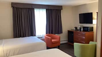 A hotel room with two beds, a television, a microwave, and a desk with a chair.