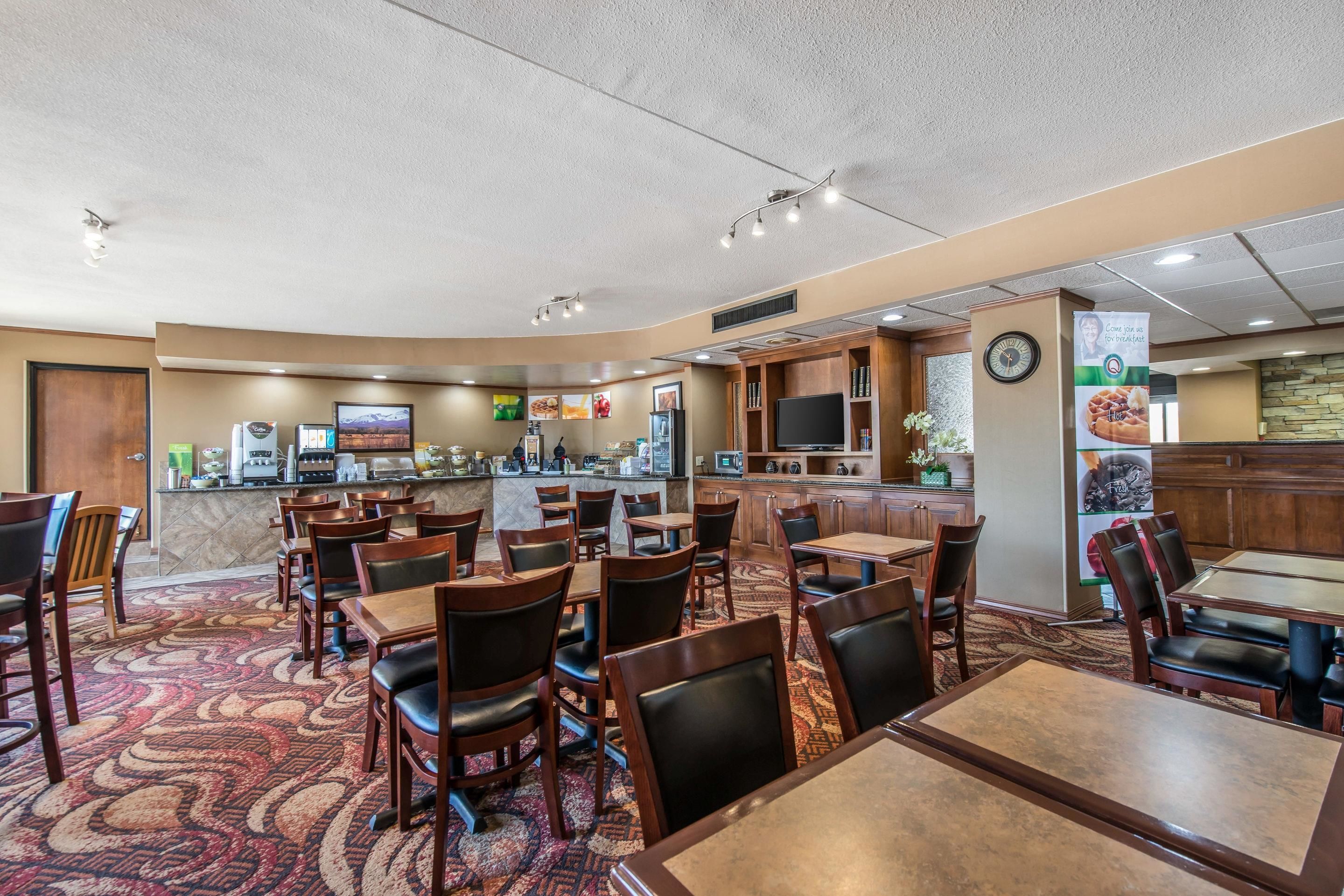 A restaurant with multiple tables and chairs, a counter with a menu, and a clock on the wall.