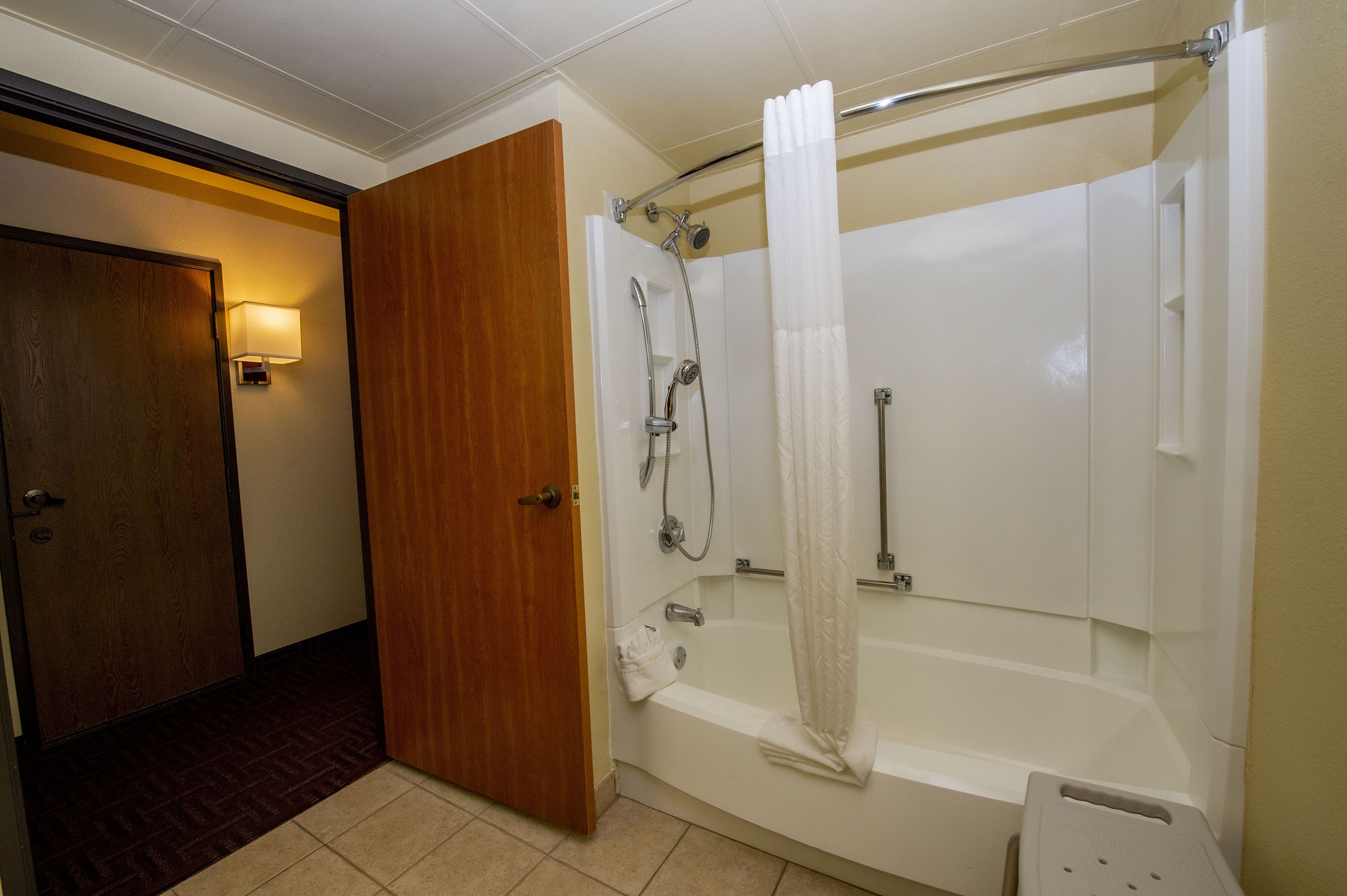 Un baño con ducha, bañera y puerta de madera.