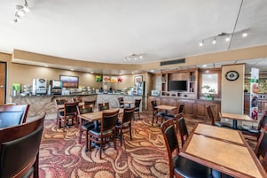 Un restaurante con una zona de bar, varias opciones de asientos y una cocina al fondo.