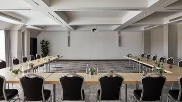 Une salle de conférence avec une longue table, des chaises et un projecteur fixé au plafond.