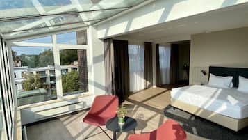 Une chambre d’hôtel moderne avec un plafond en verre, un lit, une petite table et deux chaises.