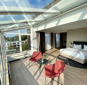 Una habitación de hotel moderna con techo de cristal, una cama, una mesita y dos sillas.