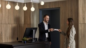 Un bureau moderne avec des murs recouverts de panneaux en bois, un bureau doté d’un ordinateur et un éclairage suspendu.