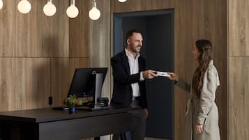 A modern office setting with wooden panel walls, a desk with a computer, and pendant lighting.