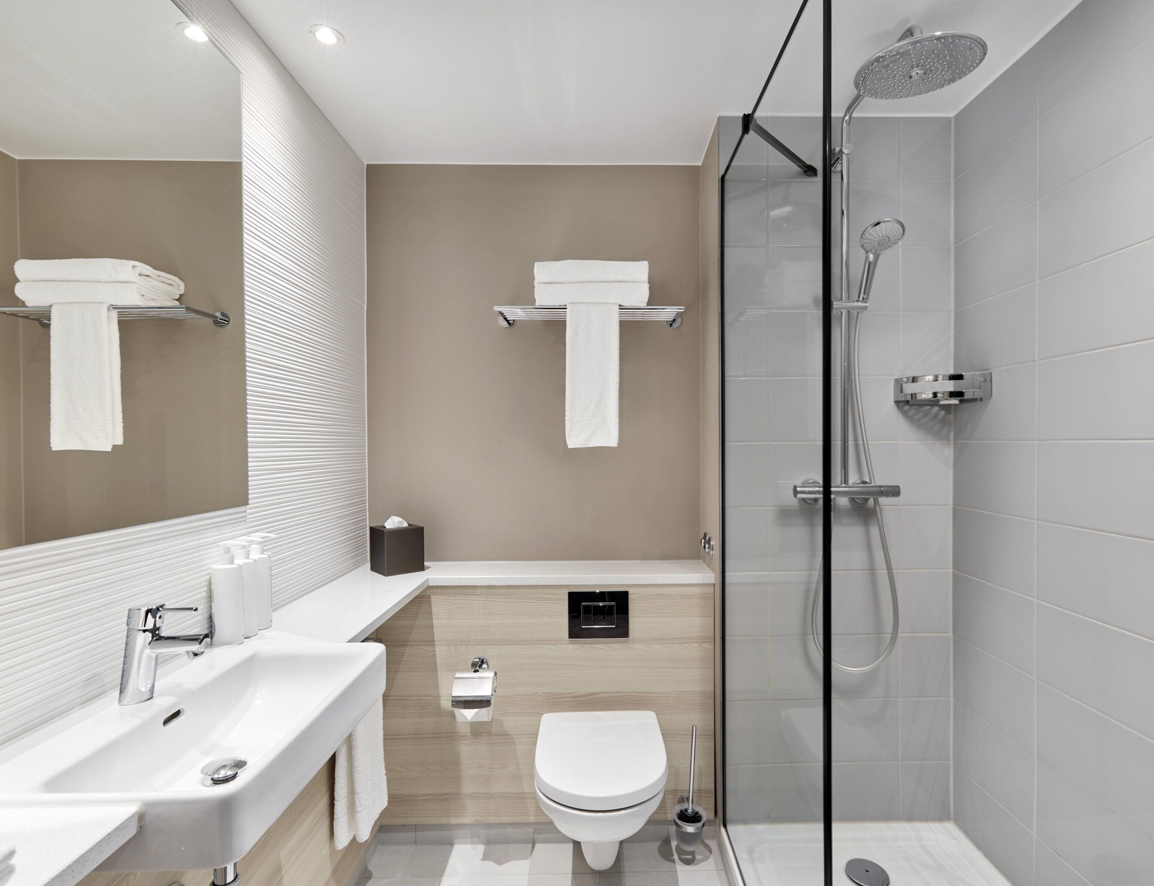 A modern bathroom with a glass-enclosed shower, a white sink, and a toilet.