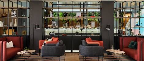 Un hall d’hôtel moderne avec deux canapés, une table basse et une bibliothèque remplie de livres et d’objets décoratifs.