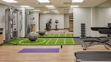 A gym with exercise equipment, a mirror, and a wall-mounted dumbbell rack.