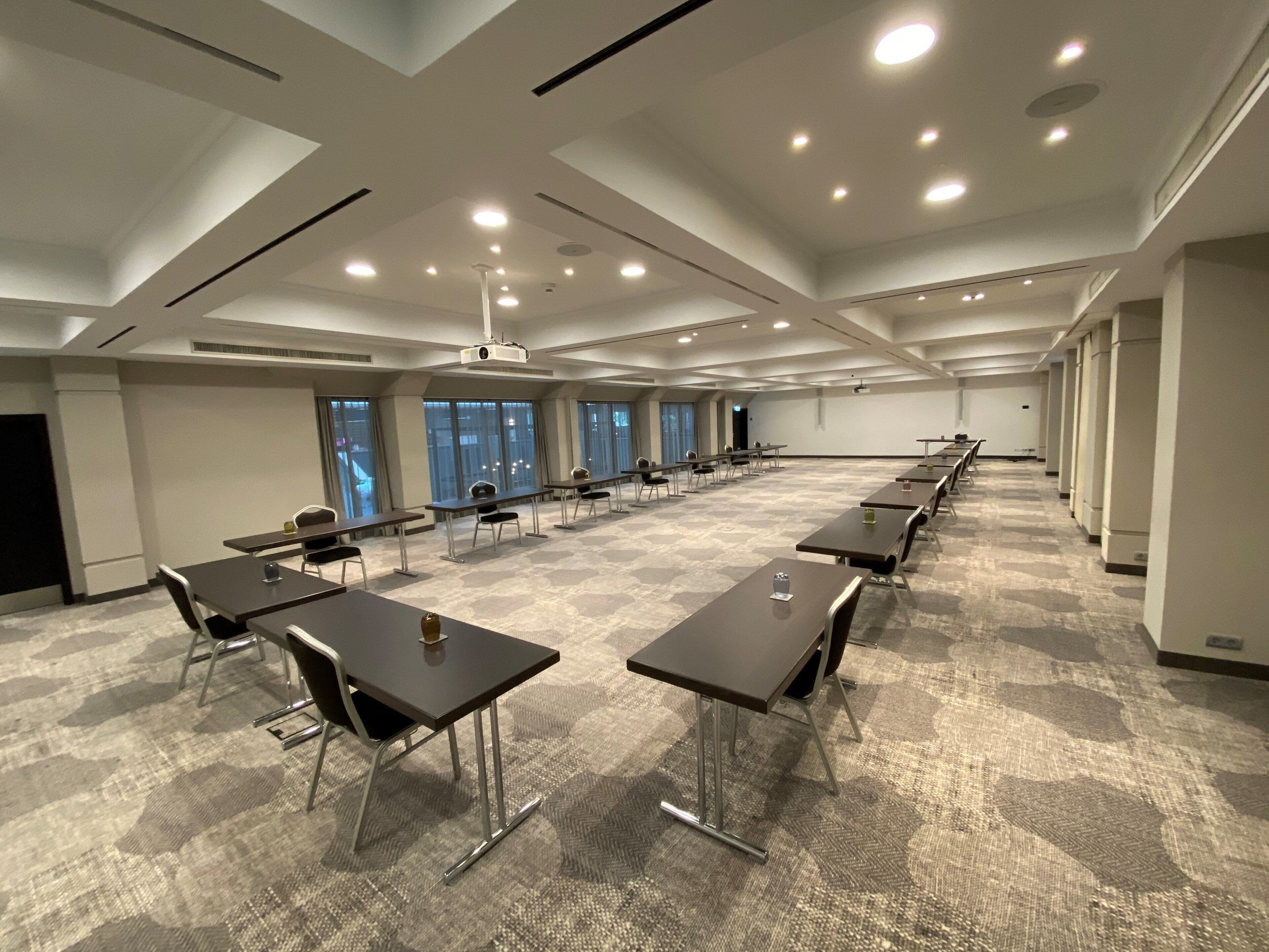 A conference room with tables, chairs, a projector, and large windows.