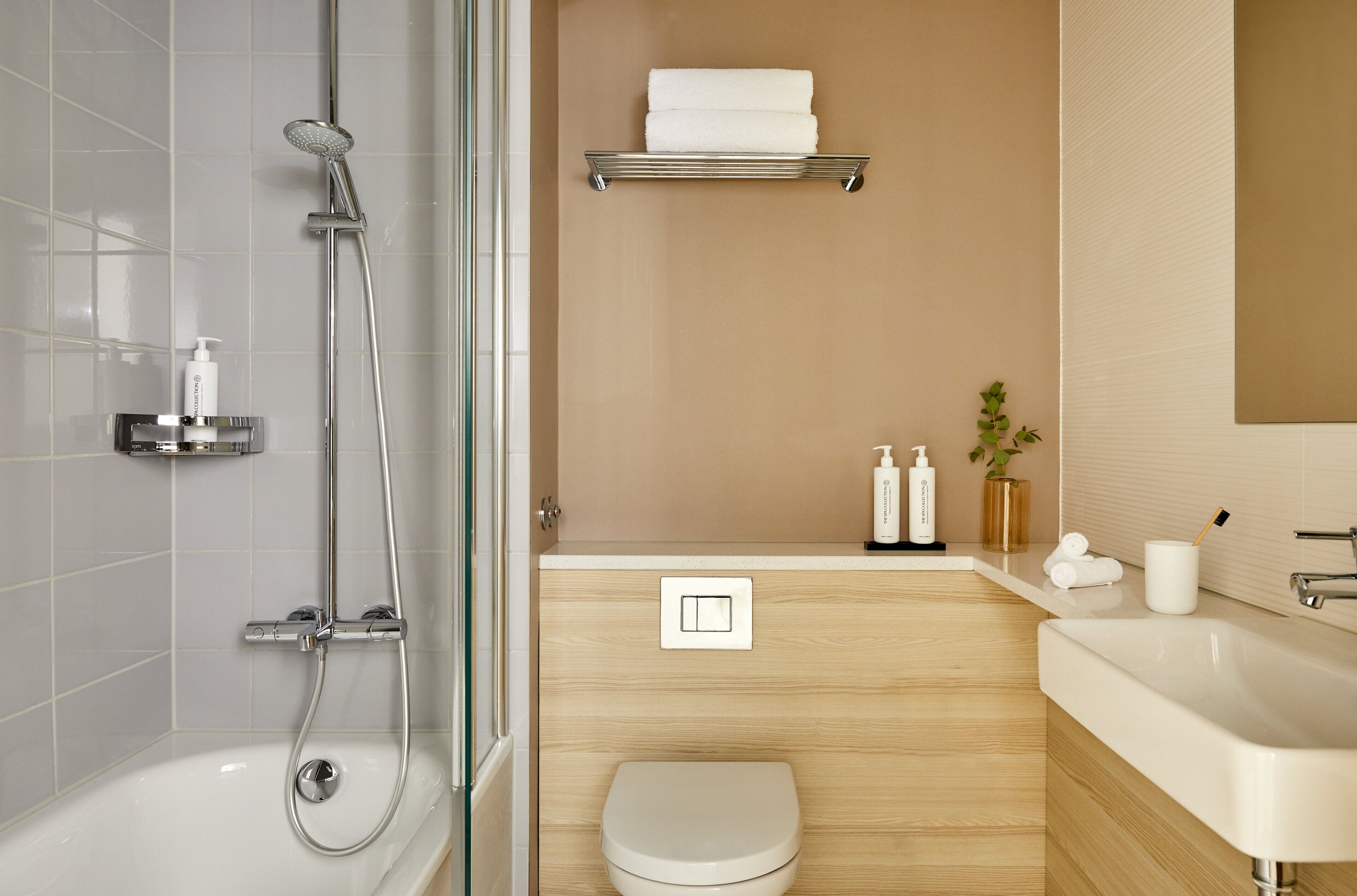 A modern bathroom with a shower, toilet, sink, and a towel rack.