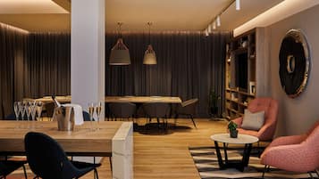 A modern living room with a wooden dining table, black and pink chairs, a coffee table, and a bookshelf.