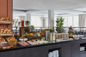 Un bufé con diferentes opciones de comida y bebidas, como pan, frutas, verduras y productos lácteos.
